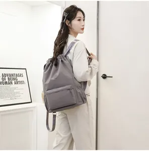 Vue détaillée du sac à dos de sport gris à cordon porté par un mannequin dans un cadre décontracté.