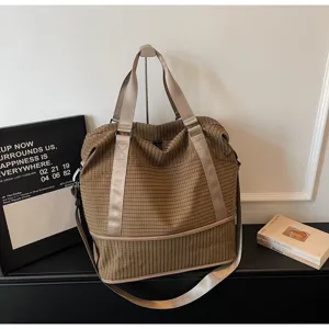 Close-up of brown checkered travel bag featuring expandable design and reinforced straps