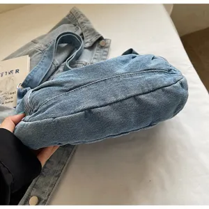 Detail showing texture of blue denim dumpling bag with high-capacity design and stitching
