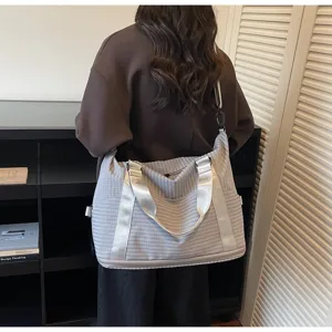 Lightweight grey striped travel bag with adjustable strap shown on model shoulder