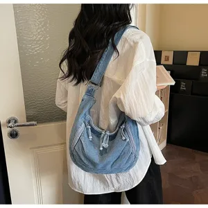 Model carrying a retro light blue denim dumpling bag in a modern interior setting