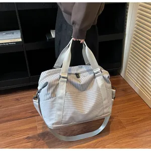 Detailed view of a large striped travel bag being held in a stylish indoor setting
