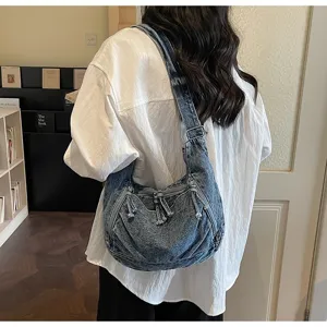 Close-up of vintage denim dumpling shoulder bag with multiple zippers and tassels