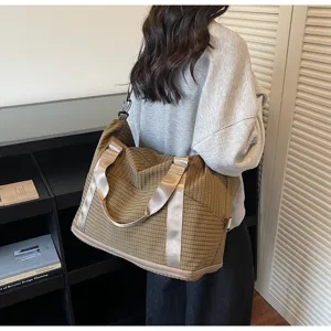 Woman wearing a large brown checkered travel bag showing its generous size and style