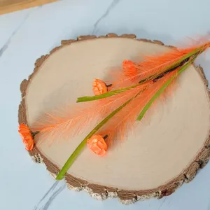 Détail d'une branche de fleur de roseau artificiel orange sur un socle en bois naturel