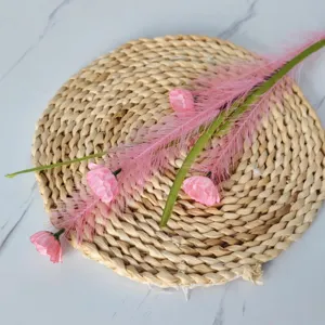 Vue détaillée d'une branche de roseau rose artificielle sur un tapis de paille