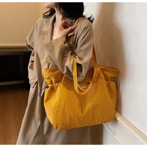 Detailed view of a large yellow waterproof tote bag worn by a professional model