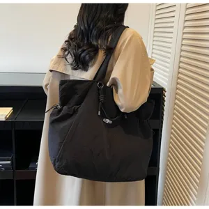 Large black waterproof travel tote bag worn over the shoulder by a model.