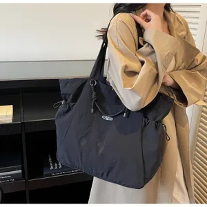 Detailed view of the large capacity black waterproof travel shoulder bag worn by a model
