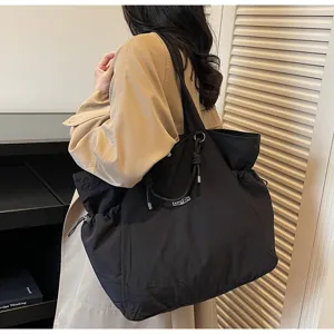 Large black waterproof tote bag worn by a model in a stylish commute scene