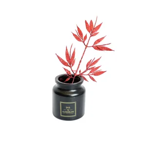 Red glitter artificial bamboo leaves branch with black vase for Christmas home decor detail.