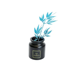 Artificial blue glitter bamboo leaves in black vase for Christmas home decor and tabletop.