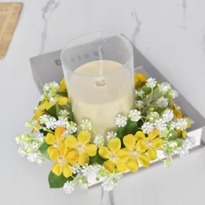 Kunstmatige bloemenkaarsring met gele en witte bloesems geplaatst op een boek en marmeren tafel