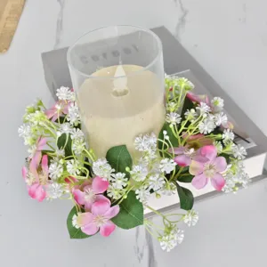 Gedetailleerde weergave van kunstbloemenkrans rond een glazen kandelaar op een marmeren tafel