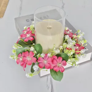 Detailweergave van een roze en witte kunstmatige bloemenkrans rond een kandelaar op een tafel