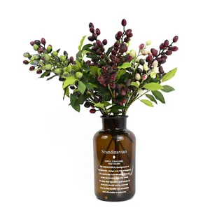 Mazzo di rami di bacche di olive artificiali con un ben vaso di vetro per decorazione