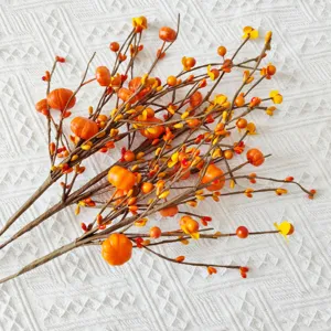 Close-up view of artificial orange berry branches with mini pumpkins for fall harvest decor