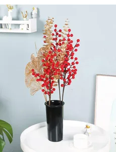 Vista detallada de bayas rojas artificiales y hojas doradas decorativas en un jarrón negro