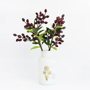 Dettaglio ramo di bacche artificiali in vaso bianco per decorazione casa e feste.
