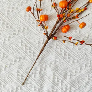 Close-up of decorative artificial branch with orange pumpkins and berries for harvest decor