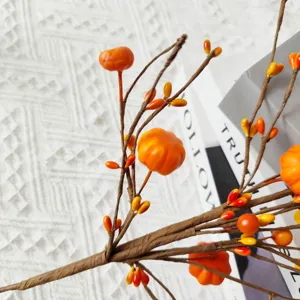 Close-up of artificial orange berry branch with miniature pumpkins for autumn decor