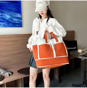 Detailed macro shot of large orange and white travel bag carried by a lifestyle model