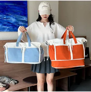 Model holding large capacity orange and blue canvas travel bags for fitness and outdoor use.