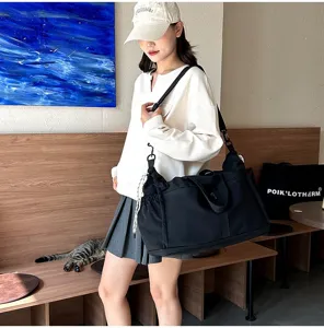 Large capacity black travel bag shown on model in a cozy indoor lifestyle setting