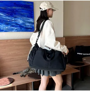 Black large capacity travel bag worn as crossbody in a modern lifestyle setting