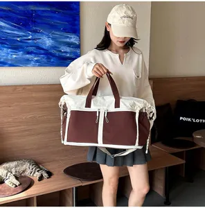 Asian model holding a large brown and white canvas duffel bag in a cozy cafe setting.