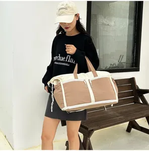 Detailed shot of large capacity tan travel bag carried by a model outdoors