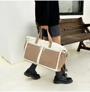 Model holding a brown and white large capacity travel bag near a wooden bench
