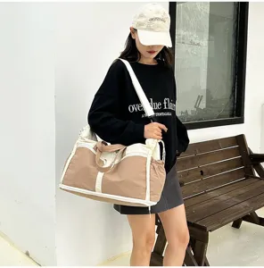 Female model carrying a large khaki and white canvas gym bag outdoors