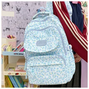 Close-up of a blue leopard print backpack with multiple zippers in a school setting.