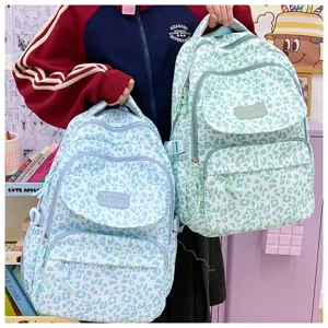 Detailed view of student holding blue and mint green leopard print school bags