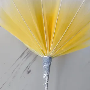 Gros plan de pétales de fleurs artificielles en filet jaune avec tige argentée mariage.
