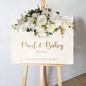 Detailansicht künstlicher weißer Rosen und Orchideen auf einem Hochzeitsschild aus Holz
