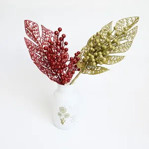 Artificial glitter leaves and berry stems in vase for Christmas holiday home decoration setup.