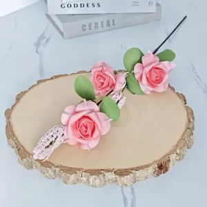 Detailansicht von künstlichen rosa Schaumrosen mit drei Köpfen auf einer rustikalen Holzscheibe