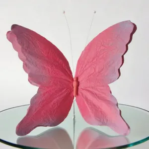 Detail shot of a gradient pink 3D butterfly paper art decor with wire antennae for display.