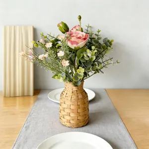 Kunstmatige roze rozen bloemboeket met eucalyptus in geweven vaas voor huisdecoratie bruiloft.