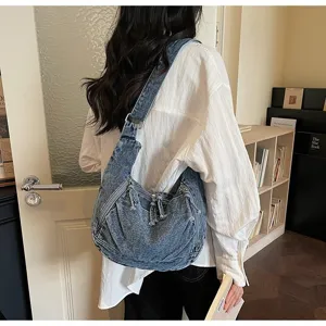 Fashion model wearing a vintage blue denim dumpling bag with multiple zipper details
