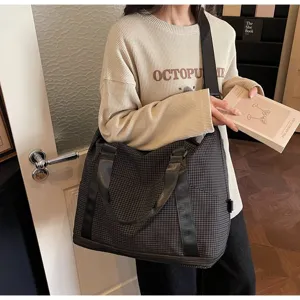 Lifestyle detail showing a large dark checkered travel bag with sturdy shoulder straps