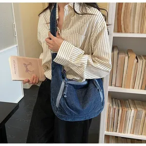 Detail shot of a vintage blue denim dumpling bag worn by a model in a library setting.