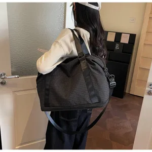 Model carrying a large capacity expandable plaid travel bag in a stylish modern indoor room