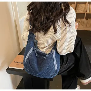 Detail of retro large denim dumpling bag worn by a student in a cozy library setting.