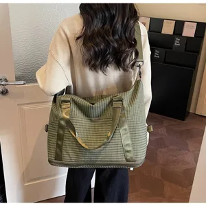 Lifestyle view of a large green checkered travel bag carried by a woman for travel.