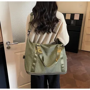 Green plaid large capacity travel bag worn as a crossbody bag by a model back view