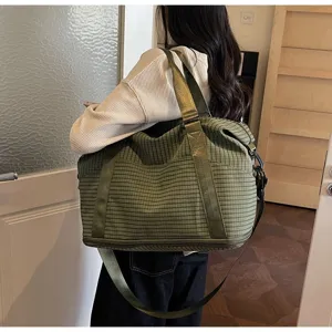 Side view of a large green checkered travel bag with durable woven straps and bottom zipper.