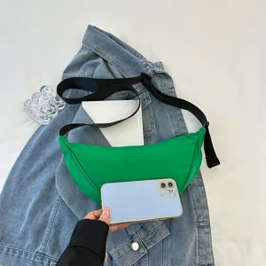 Vibrant green minimalist dumpling crossbody bag shown with smartphone for scale